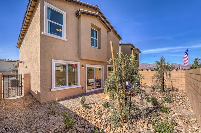 rear view of house with central air condition unit, fence, and stucco siding