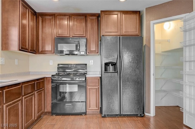 1158 Gecko Rd, Henderson, NV 89002 - kitchen with black appliances, light countertops, light wood-type flooring, and brown cabinetry