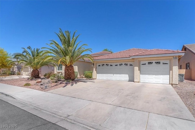 view of front of home with a tile roof, a garage, stucco siding, and driveway