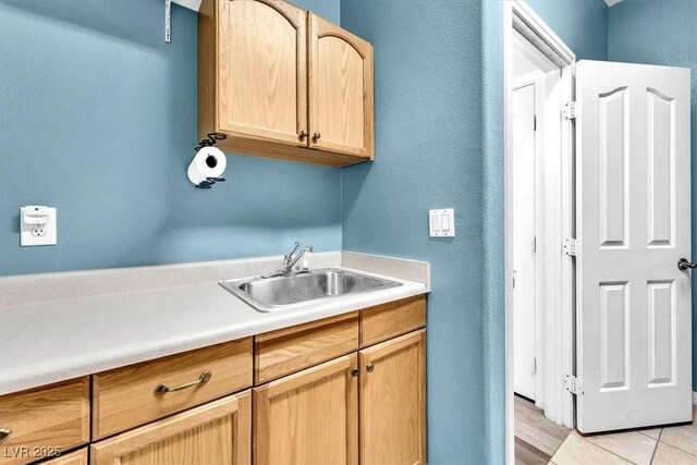 clothes washing area featuring a textured wall and a sink