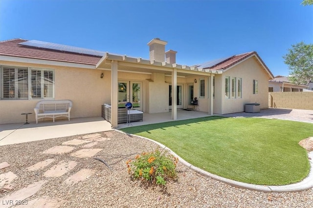rear view of house with stucco siding, solar panels, and a tile roof