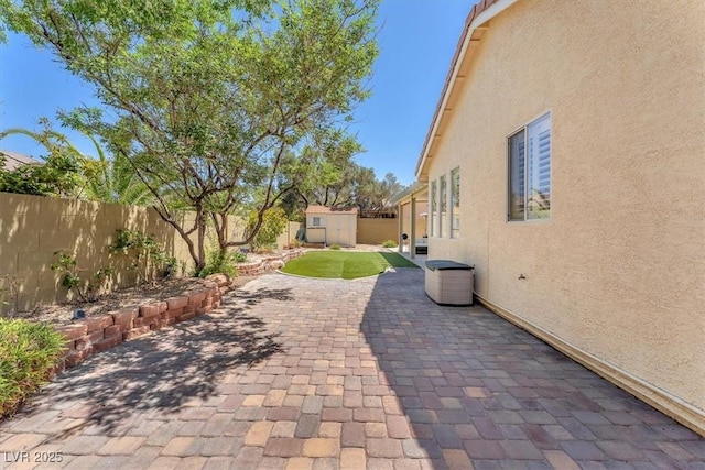 view of patio / terrace with a fenced backyard, an outdoor structure, and a storage shed