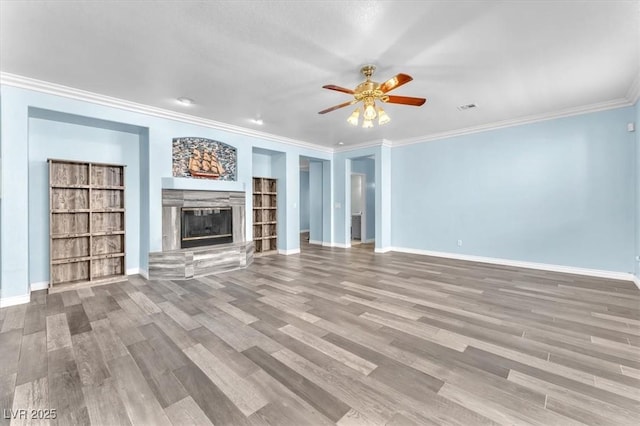 unfurnished living room featuring wood finished floors, a ceiling fan, baseboards, a glass covered fireplace, and ornamental molding
