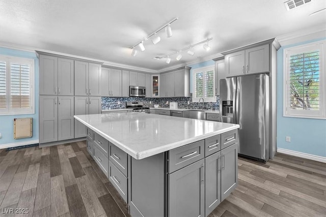 kitchen featuring gray cabinetry, baseboards, dark wood-type flooring, a kitchen island, and stainless steel appliances