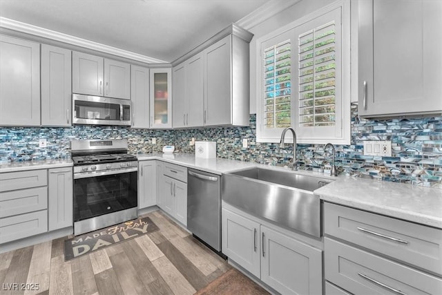 kitchen featuring light countertops, appliances with stainless steel finishes, gray cabinets, and a sink