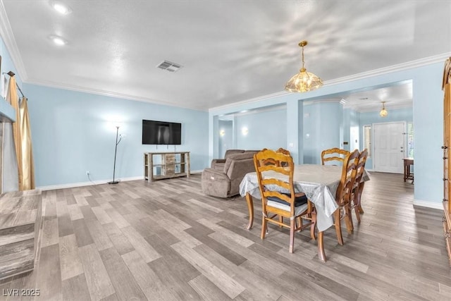 dining room featuring crown molding, baseboards, visible vents, and wood finished floors