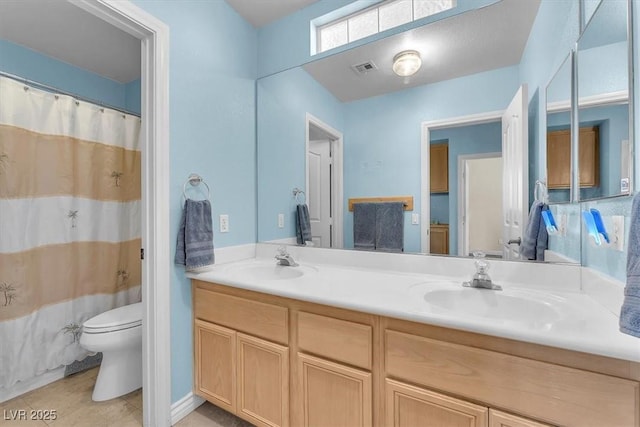 bathroom with tile patterned floors, double vanity, toilet, and a sink