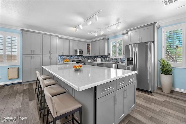 kitchen featuring a kitchen island, appliances with stainless steel finishes, gray cabinets, and dark wood-style flooring