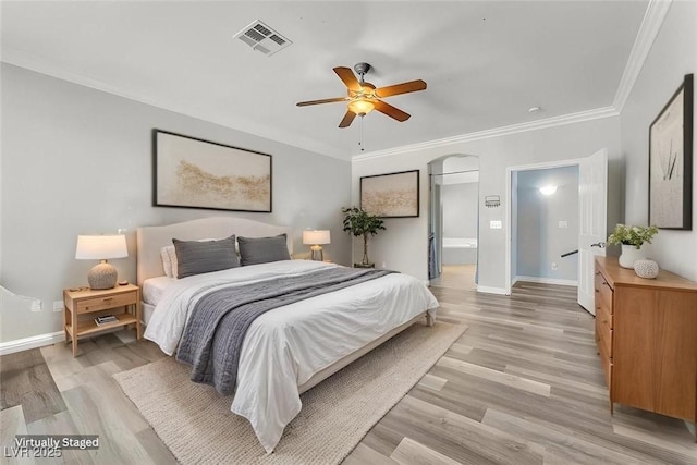 bedroom featuring visible vents, light wood-style flooring, baseboards, and arched walkways