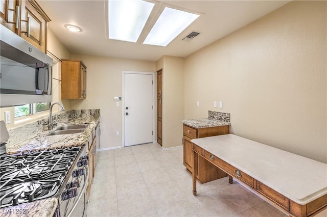 kitchen with brown cabinetry, stainless steel appliances, visible vents, and a sink