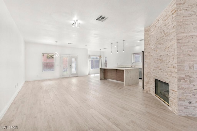 unfurnished living room featuring a wealth of natural light, light wood-type flooring, and visible vents