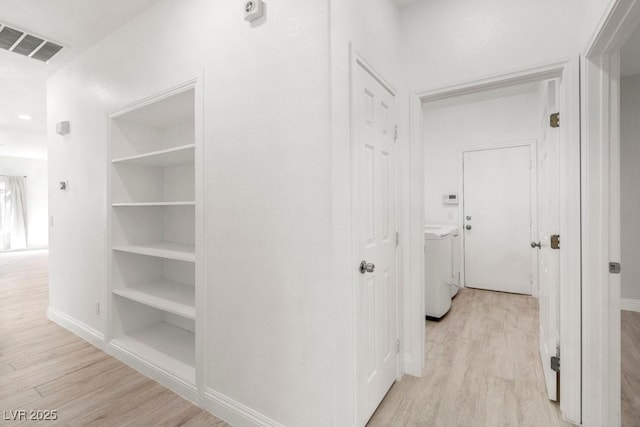 hall featuring baseboards, light wood finished floors, washer and dryer, and visible vents