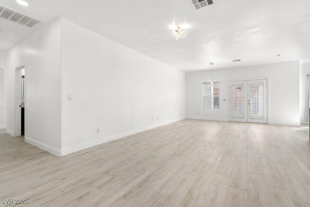 spare room featuring visible vents, light wood-style flooring, and baseboards