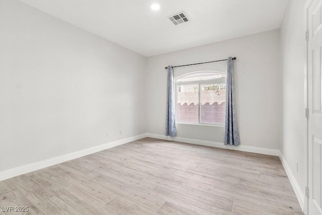 unfurnished room featuring baseboards, light wood-style flooring, and visible vents