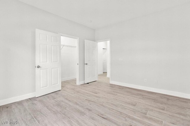 unfurnished bedroom with light wood finished floors, a closet, and baseboards