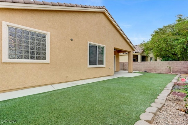 rear view of house featuring a yard, stucco siding, and fence