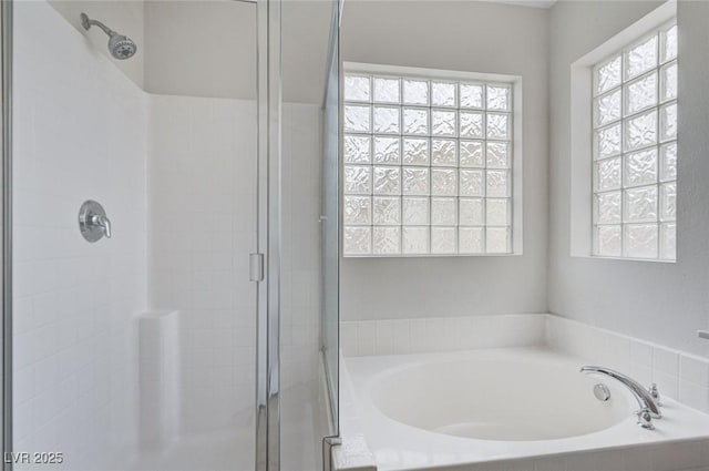 bathroom featuring a garden tub and a shower stall