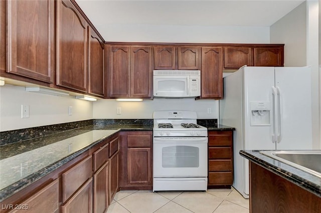kitchen featuring white appliances, dark stone counters, and light tile patterned flooring