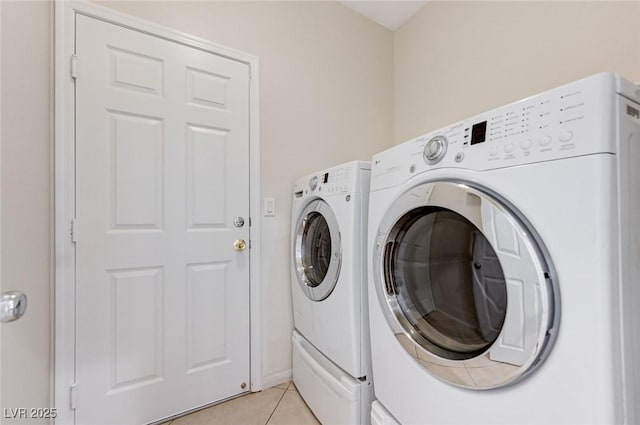 clothes washing area with washing machine and clothes dryer, laundry area, and light tile patterned flooring
