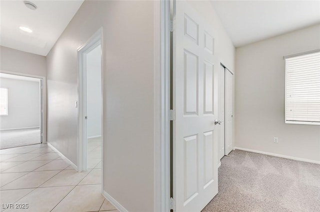 corridor featuring baseboards and light tile patterned floors
