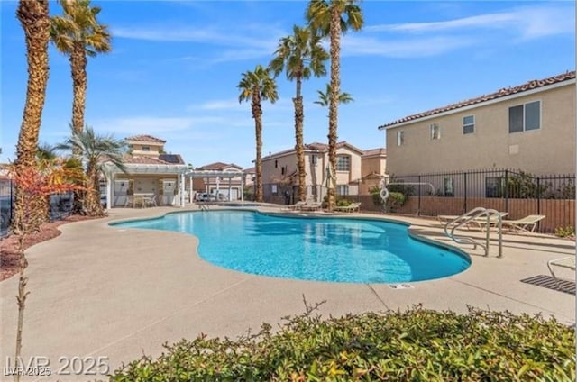 community pool featuring a patio area, fence, and a residential view