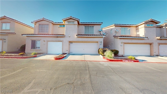view of front of house featuring stucco siding, a tiled roof, and an attached garage