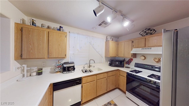 kitchen with a sink, freestanding refrigerator, visible vents, dishwasher, and gas range oven