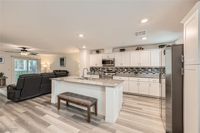 kitchen with light wood-style flooring, a sink, stainless steel appliances, white cabinetry, and visible vents