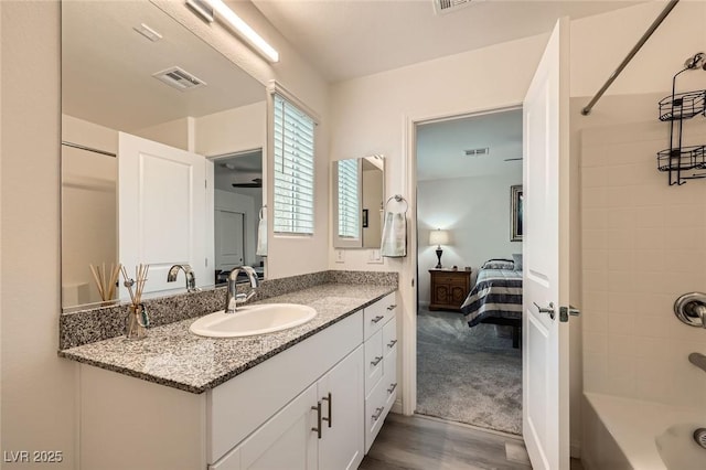 bathroom featuring shower / bath combination, vanity, visible vents, and wood finished floors