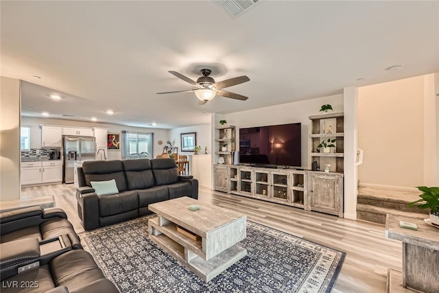 living room with light wood-type flooring, visible vents, a ceiling fan, and recessed lighting
