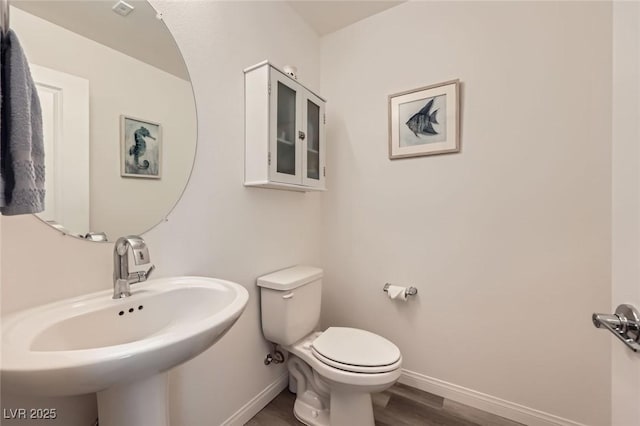 bathroom with baseboards, toilet, a sink, and wood finished floors