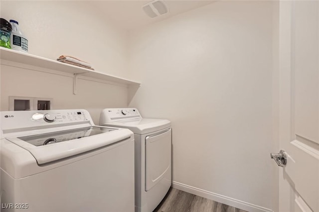 clothes washing area featuring baseboards, laundry area, wood finished floors, and washer and clothes dryer