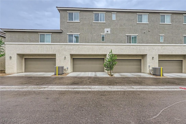 view of front of home with cooling unit, stucco siding, and a garage