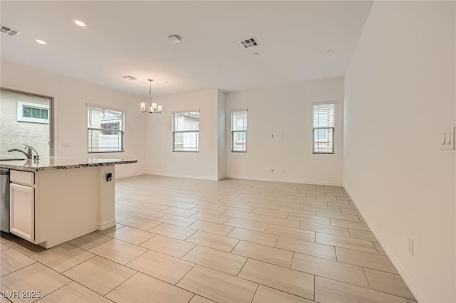 790 Sunny Sagebrush St, Henderson, NV 89011 - kitchen with light stone counters, a healthy amount of sunlight, an inviting chandelier, and visible vents