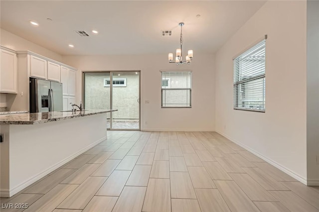 790 Sunny Sagebrush St, Henderson, NV 89011 - kitchen featuring a notable chandelier, light stone counters, visible vents, white cabinetry, and stainless steel refrigerator with ice dispenser