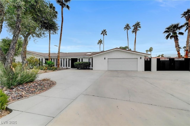 single story home with concrete driveway, stucco siding, fence, and a garage