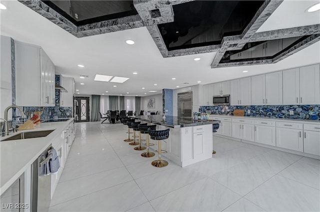 kitchen with stainless steel appliances, a sink, decorative backsplash, a breakfast bar, and recessed lighting