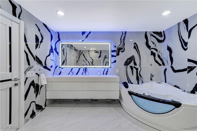full bathroom with double vanity, a whirlpool tub, tile walls, and recessed lighting