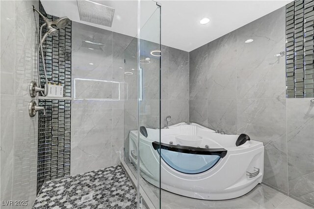 bathroom with tile walls, a whirlpool tub, a tile shower, and marble tiled floors