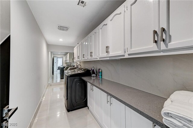 clothes washing area with cabinet space, light tile patterned flooring, and baseboards