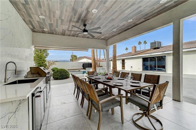 view of patio with ceiling fan, outdoor dining area, exterior kitchen, a fenced backyard, and central AC unit