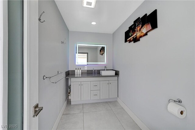 bathroom with baseboards, tile patterned floors, and double vanity