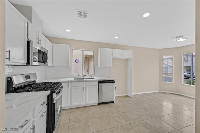 5820 Royal Castle Ln, Las Vegas, NV 89130 - kitchen featuring a sink, tasteful backsplash, light tile patterned floors, white cabinets, and appliances with stainless steel finishes