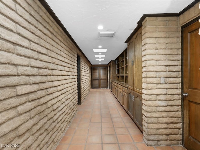 hallway featuring brick wall, visible vents, and recessed lighting