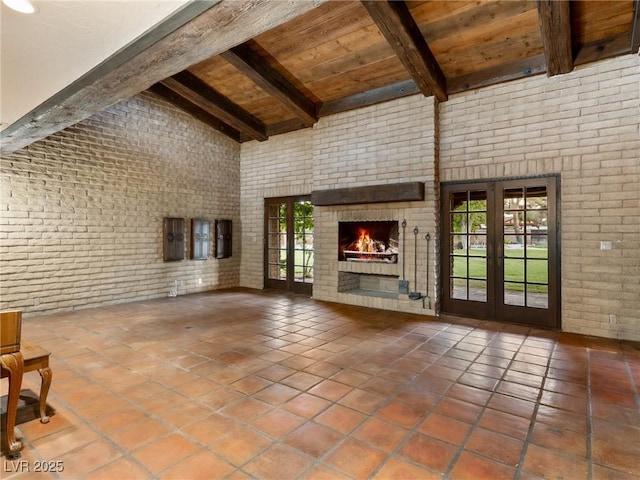 unfurnished living room featuring brick wall, beamed ceiling, wooden ceiling, and tile patterned floors