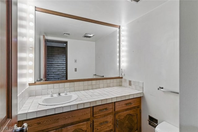 bathroom with toilet, vanity, and visible vents