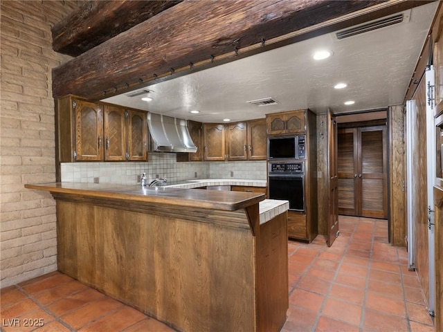 kitchen with a peninsula, oven, visible vents, wall chimney exhaust hood, and built in microwave