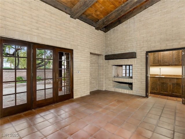 interior space featuring french doors, tile patterned floors, wooden ceiling, brick wall, and a high ceiling