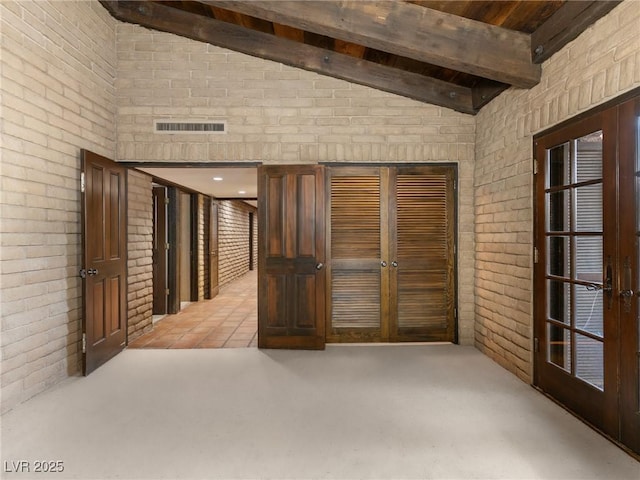 unfurnished room featuring french doors, lofted ceiling with beams, brick wall, visible vents, and light colored carpet