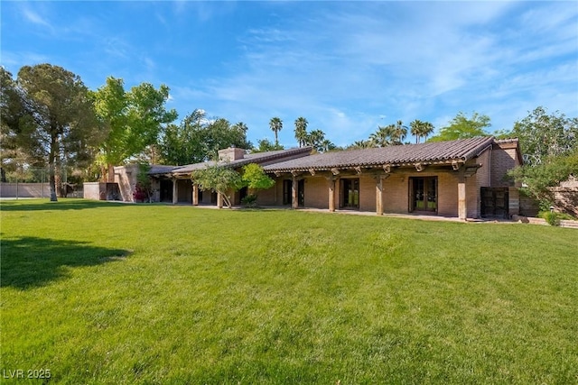 back of house with french doors and a lawn